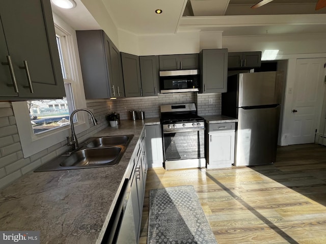 kitchen featuring sink, light hardwood / wood-style flooring, decorative backsplash, light stone countertops, and stainless steel appliances