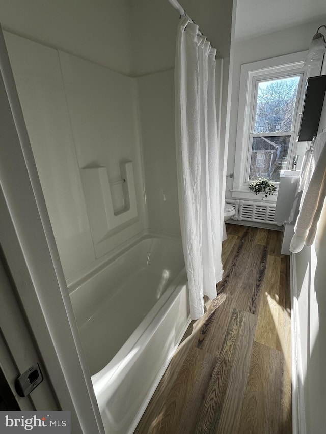 bathroom with shower / tub combo, hardwood / wood-style flooring, and toilet