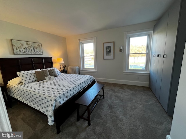 bedroom featuring dark colored carpet, radiator, and multiple windows