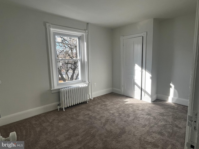 empty room featuring dark carpet and radiator