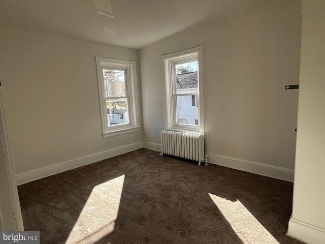 carpeted empty room featuring radiator heating unit