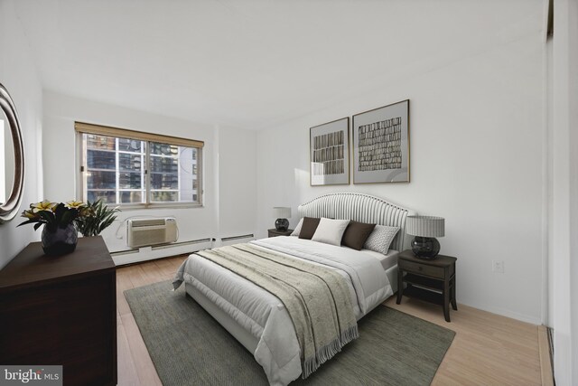 bedroom featuring a wall mounted AC, a baseboard heating unit, and light wood-type flooring