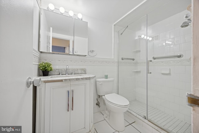 bathroom with an enclosed shower, vanity, tile walls, tile patterned flooring, and toilet