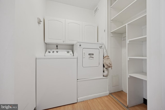 laundry area with cabinets, light wood-type flooring, and separate washer and dryer