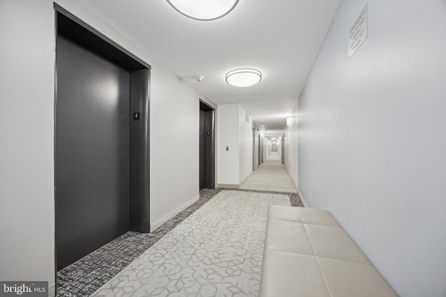 hall featuring elevator and light colored carpet