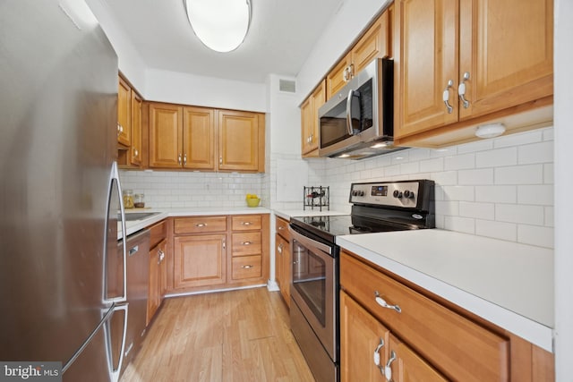 kitchen featuring backsplash, stainless steel appliances, and light hardwood / wood-style floors