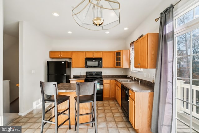 kitchen featuring black appliances, a kitchen breakfast bar, a kitchen island, and sink