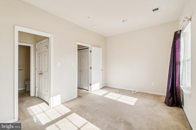 unfurnished bedroom with light carpet and connected bathroom