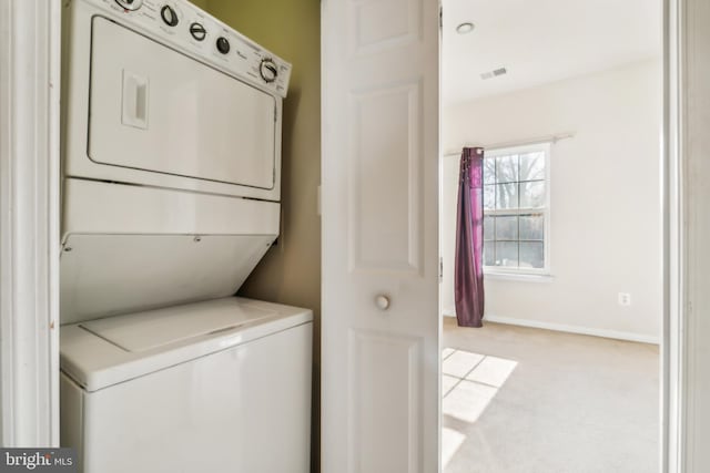 laundry room with light colored carpet and stacked washer and clothes dryer