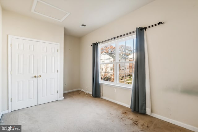 unfurnished bedroom with light colored carpet and a closet