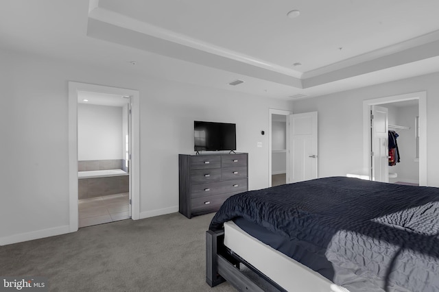 bedroom featuring ensuite bath, a raised ceiling, light colored carpet, a walk in closet, and a closet