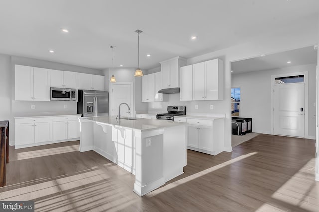 kitchen featuring pendant lighting, a kitchen island with sink, hardwood / wood-style flooring, white cabinetry, and stainless steel appliances