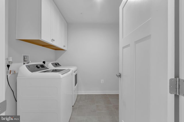 clothes washing area with washer and clothes dryer and cabinets