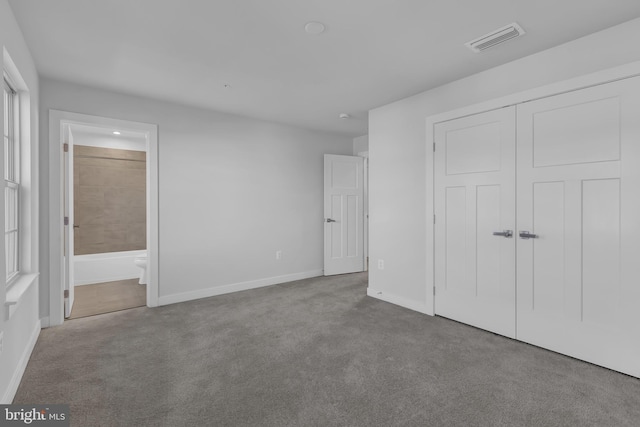 unfurnished bedroom with ensuite bathroom, a closet, and light carpet