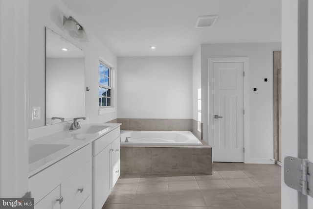 bathroom featuring tile patterned flooring, a relaxing tiled tub, and vanity