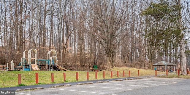 view of parking / parking lot with a playground and a lawn