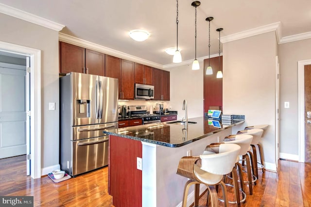 kitchen featuring pendant lighting, sink, stainless steel appliances, and light hardwood / wood-style flooring