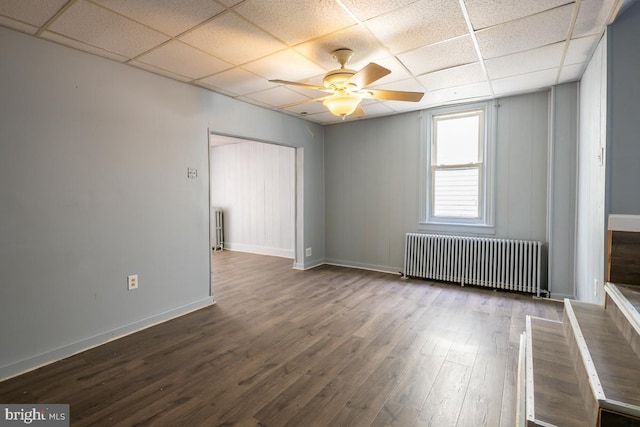 spare room featuring a paneled ceiling, ceiling fan, wood-type flooring, and radiator