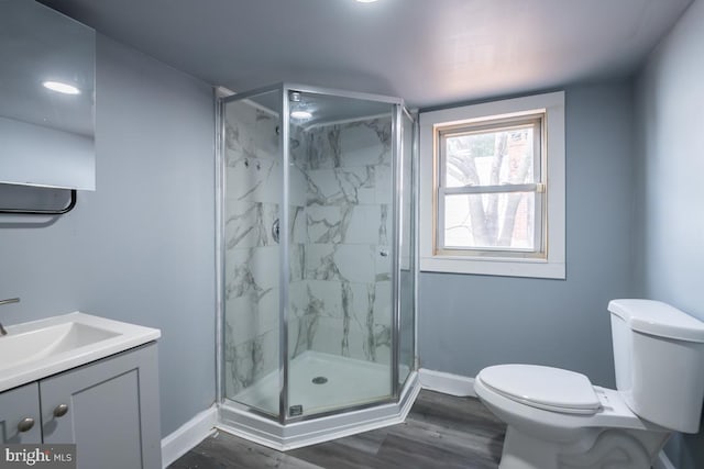 bathroom featuring vanity, wood-type flooring, an enclosed shower, and toilet