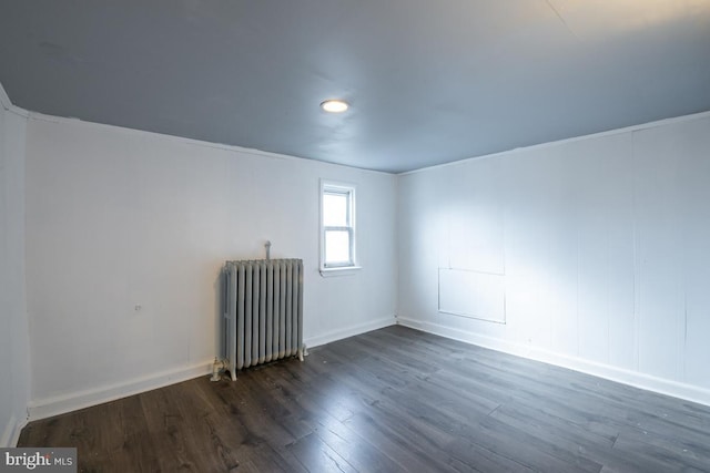 spare room with radiator heating unit and dark wood-type flooring