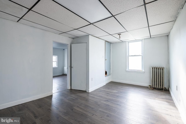 unfurnished room featuring hardwood / wood-style floors, a paneled ceiling, and radiator