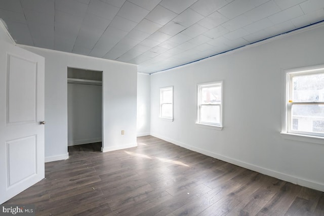 unfurnished bedroom with dark hardwood / wood-style flooring, multiple windows, and crown molding