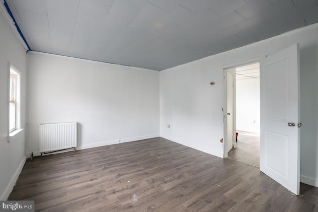 spare room with hardwood / wood-style flooring and radiator heating unit