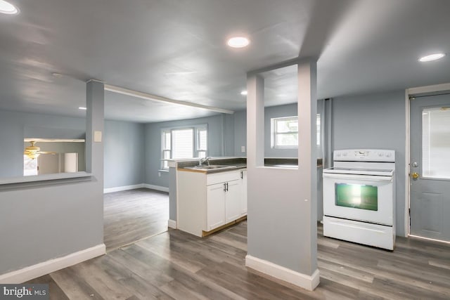 kitchen with white range with electric cooktop, sink, white cabinets, and hardwood / wood-style floors