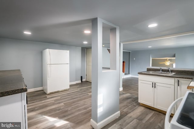 kitchen with white cabinetry, sink, white refrigerator, stove, and wood-type flooring