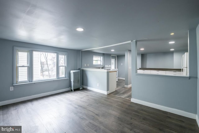 unfurnished living room featuring radiator and dark wood-type flooring