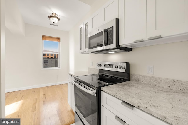 kitchen featuring appliances with stainless steel finishes, light hardwood / wood-style floors, white cabinetry, and light stone counters