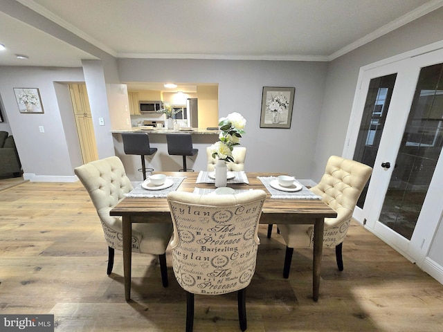 dining space featuring french doors, light hardwood / wood-style floors, and ornamental molding