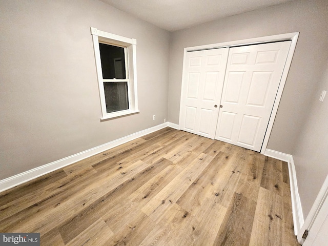 unfurnished bedroom with light hardwood / wood-style flooring and a closet