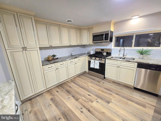 kitchen with tasteful backsplash, sink, appliances with stainless steel finishes, and cream cabinets