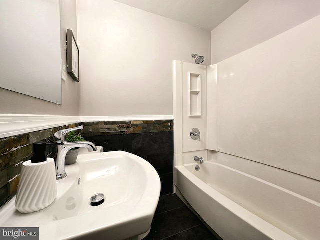 bathroom with tile patterned floors, shower / bathtub combination, sink, and tile walls