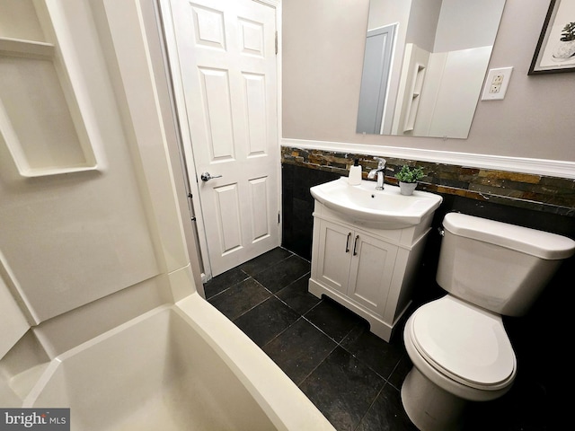 bathroom featuring tile patterned floors, vanity, toilet, and tile walls