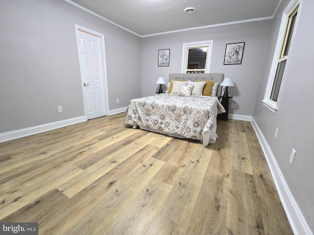 bedroom with crown molding and light hardwood / wood-style floors