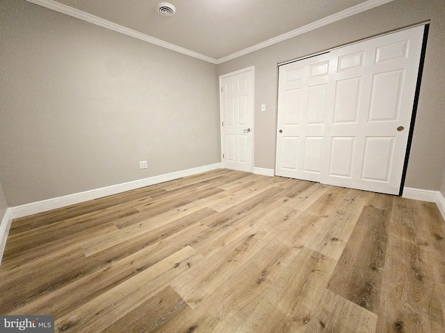 unfurnished bedroom with light hardwood / wood-style floors, crown molding, and a closet