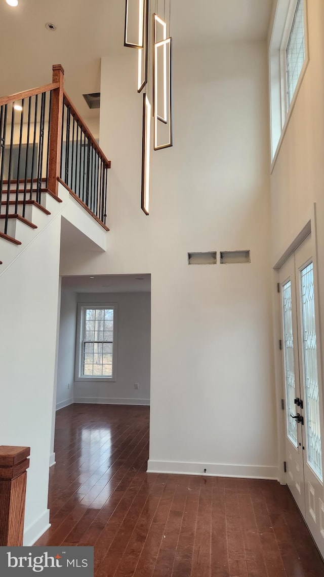 foyer with dark hardwood / wood-style flooring, a towering ceiling, and french doors