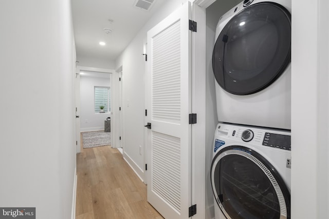 laundry area featuring light wood-type flooring and stacked washer / dryer