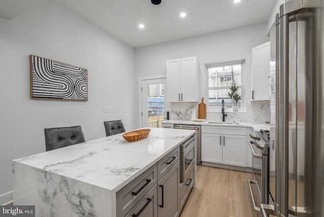 kitchen featuring a kitchen breakfast bar, sink, white cabinets, and stainless steel appliances