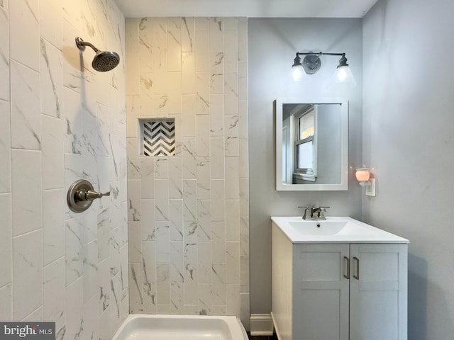 bathroom with tiled shower and vanity