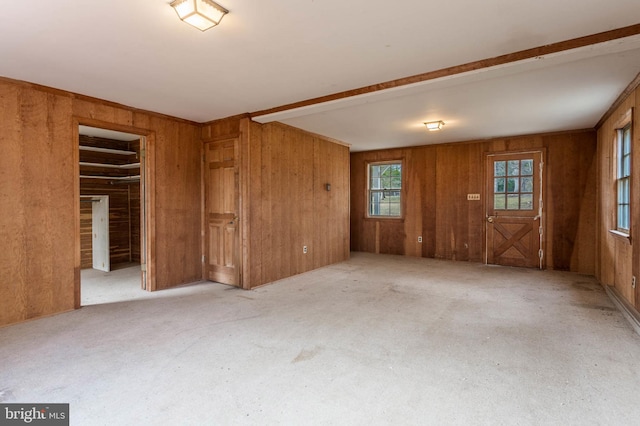 carpeted empty room featuring wooden walls