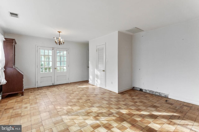 empty room with french doors, light parquet flooring, and an inviting chandelier