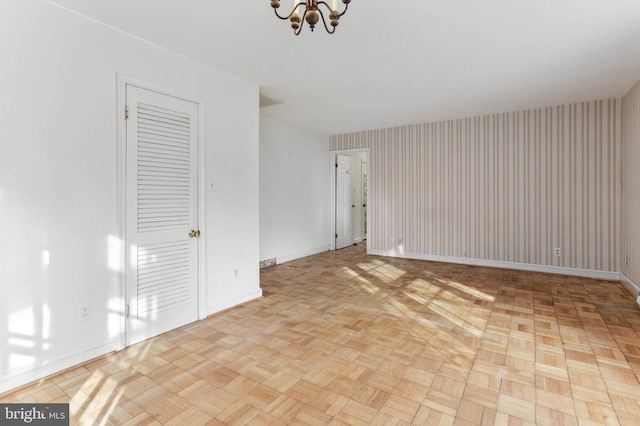 unfurnished room with a chandelier and light parquet floors