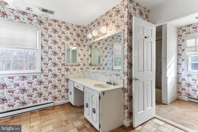 bathroom with parquet flooring, vanity, and a baseboard heating unit