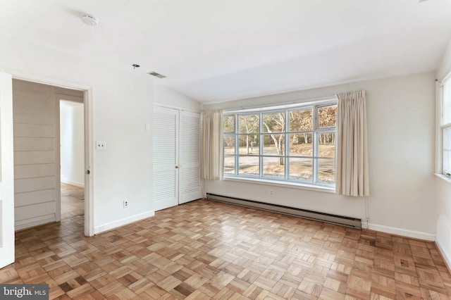 unfurnished room featuring light parquet floors, a baseboard radiator, and vaulted ceiling