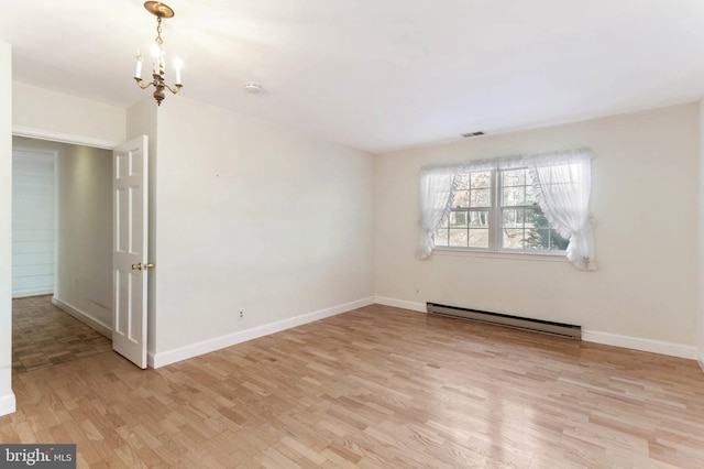 empty room featuring a chandelier, light hardwood / wood-style floors, and a baseboard heating unit