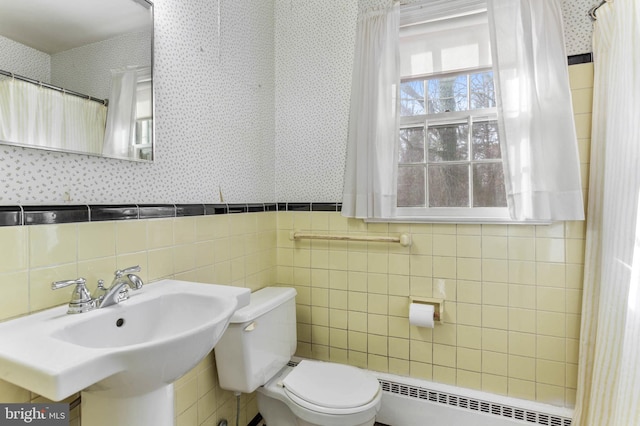 bathroom featuring tile walls, toilet, radiator, and sink