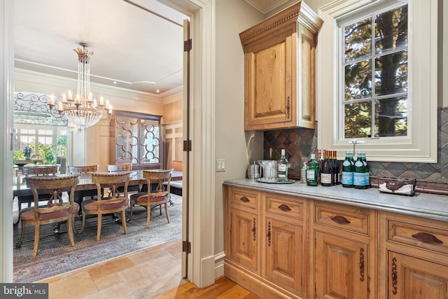 bar featuring an inviting chandelier, ornamental molding, decorative light fixtures, and backsplash